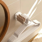 Estante organizador de pared plegable con ropa colgada